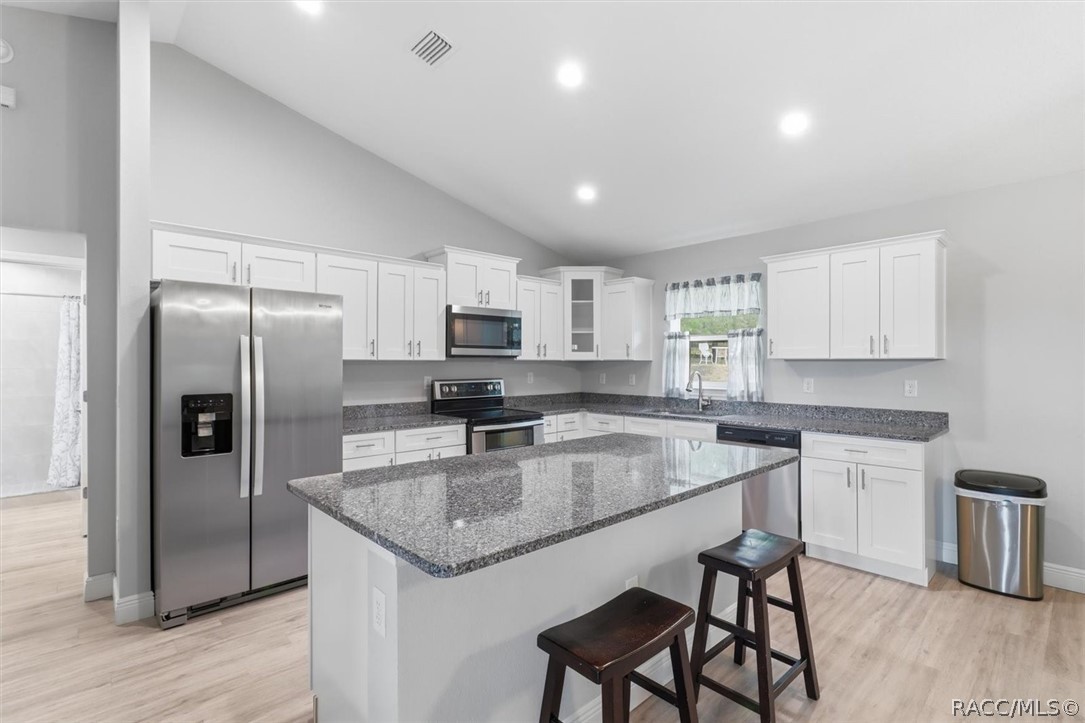 Taller white wood cabinets with crown molding, soft-close drawers, corner cabinet with glass front door, granite countertops and stainless steel appliances