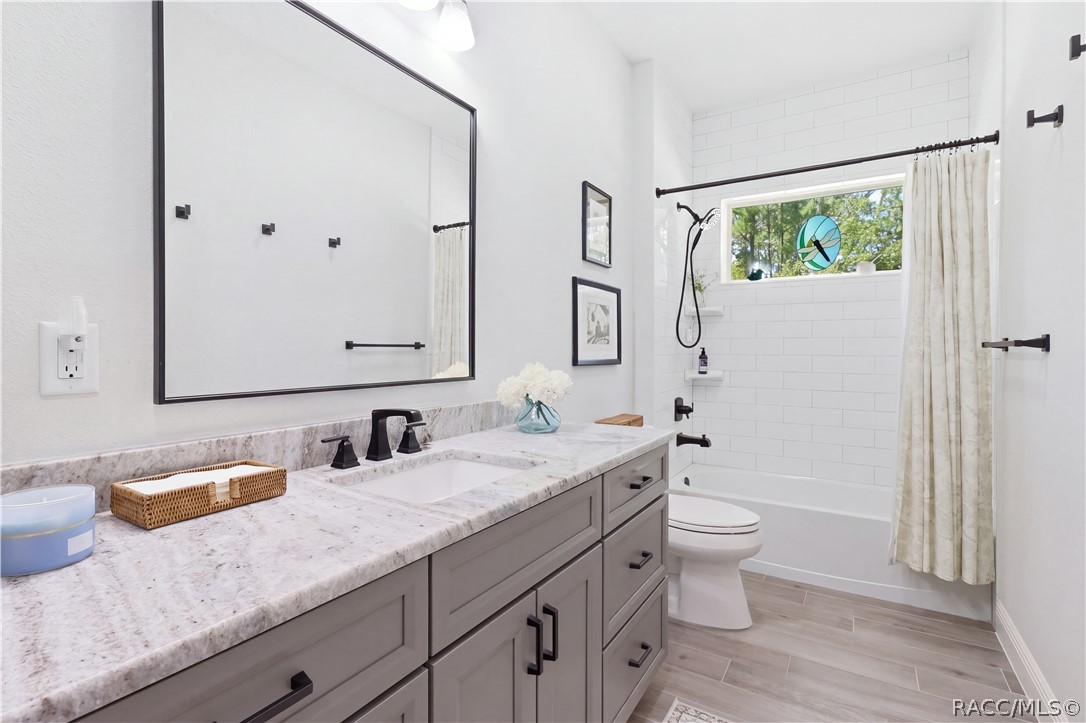 GUEST BATHROOM  Stylish guest bath features a large vanity w/ abundant storage, granite countertop, oversized framed mirror & matte-black fixtures. The tub/tiled shower is surrounded by classic white tile & accented by a horizontal window bringing in natural light.