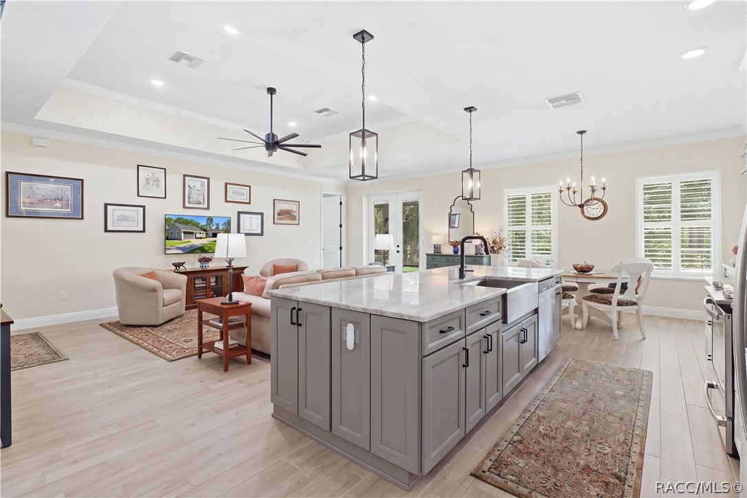 KITCHEN + GREAT ROOM  Oversized contrasting island anchors the open floor plan w/ expansive stone-look counters, farmhouse-style stainless sink, statement faucet, pendant lighting & abundant cabinetry.