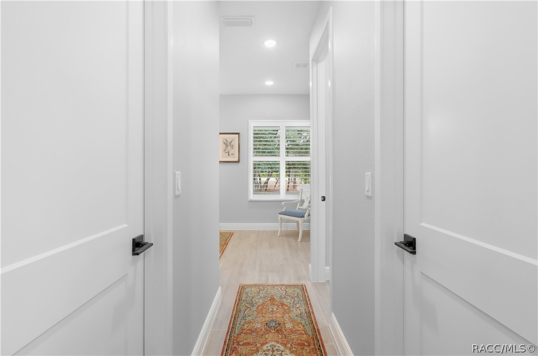 PRIVATE PRIMARY SUITE HALLWAY  Clean, thoughtfully designed hallway connects the primary bedroom to the ensuite bath, featuring recessed lighting, porcelain tile flooring, crisp white trim & contemporary black door hardware.
