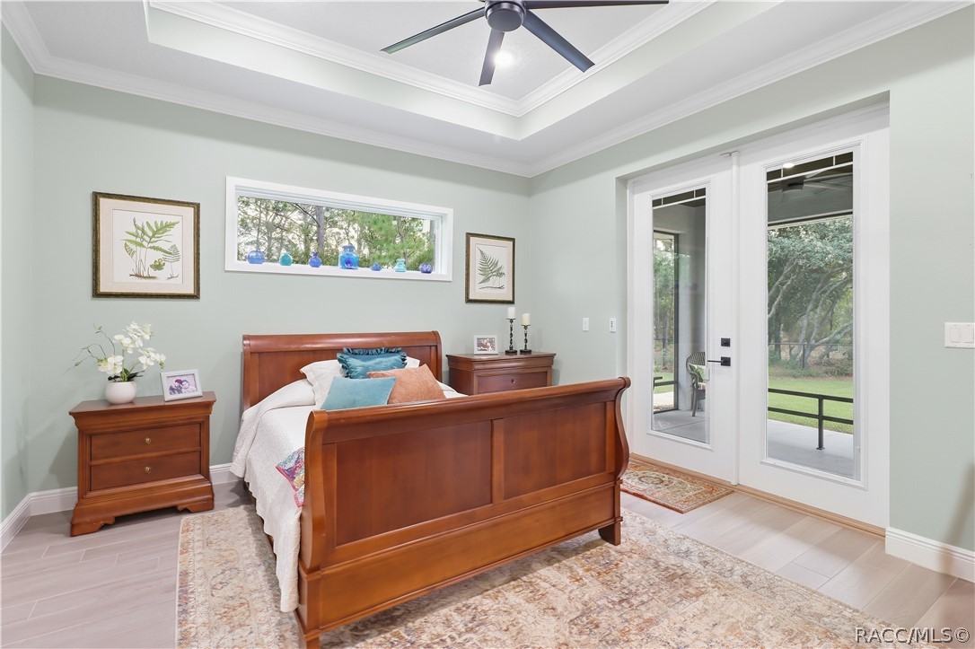 BEDROOM RETREAT  Spacious bedroom features a tray ceiling w/ crown molding, modern ceiling fan, high horizontal accent window, light flooring & glass doors opening to a covered screened outdoor area.