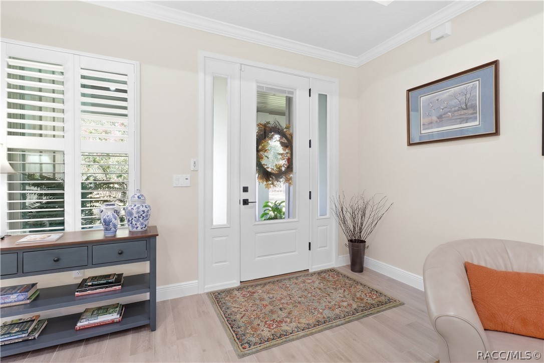 BRIGHT FOYER  Glass-paneled front door w/ sidelights fills the entry w/ natural light; plantation shutters, crown molding, wide baseboards & light-toned flooring add a polished finish.