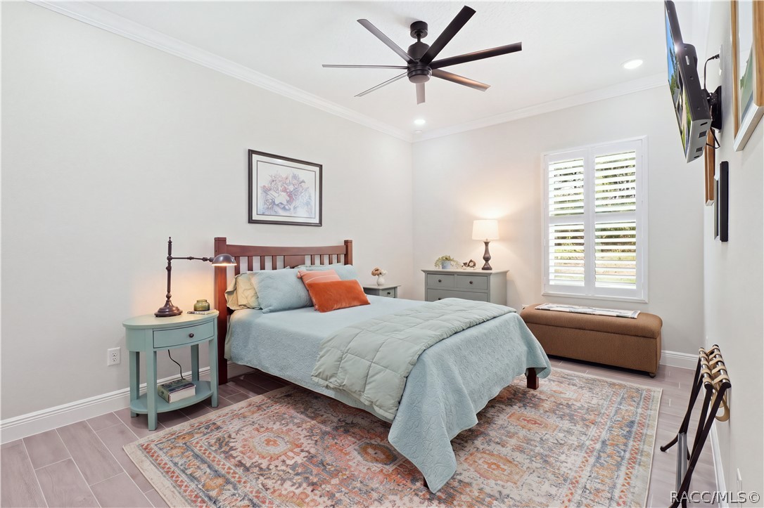 GUEST BEDROOM 1  Bright, generously sized guest bedroom features crown molding, recessed lighting, oversized modern ceiling fan, porcelain tile flooring & plantation shutters for a polished, comfortable retreat.