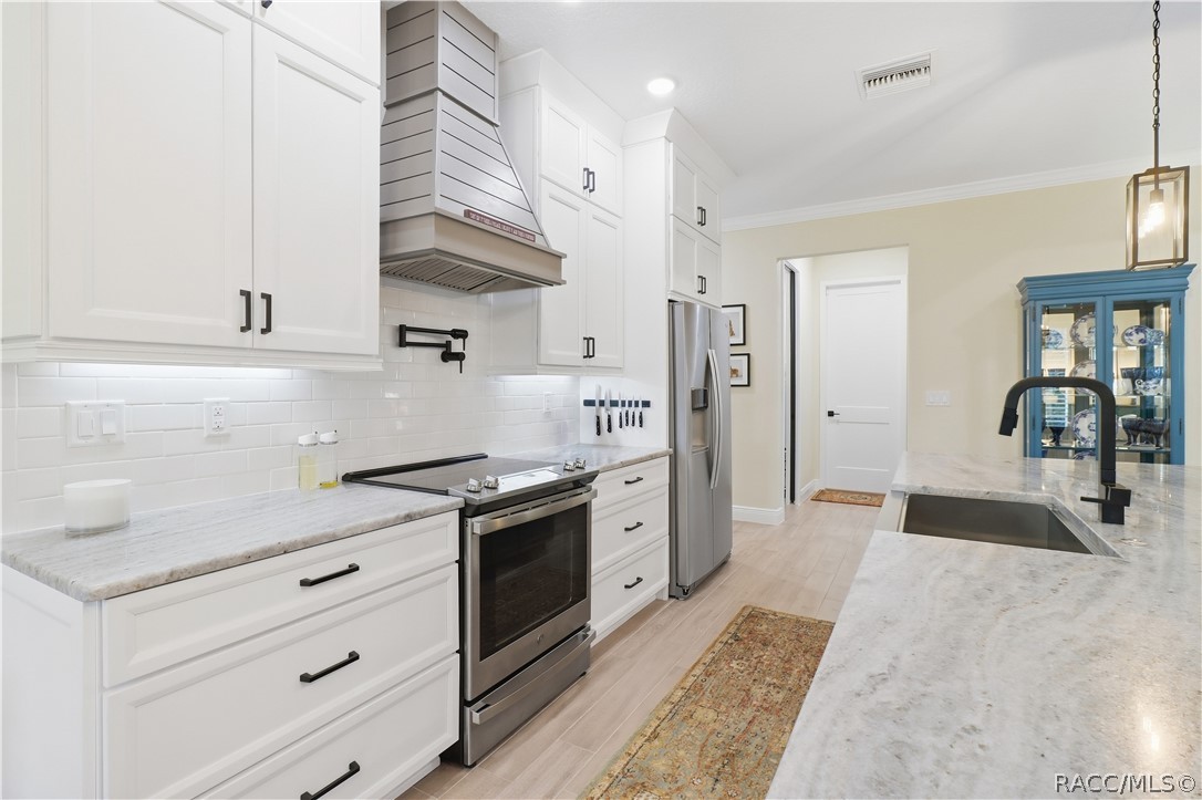 DESIGNER KITCHEN  Tall white cabinetry, black hardware, under-cabinet lighting, subway-tile backsplash, stainless appliances, custom-style hood & pot filler combine style w/ everyday function.