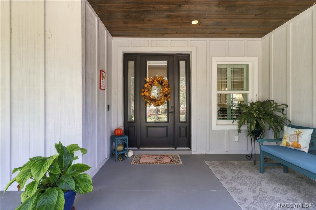 FRONT DOOR DETAIL  Striking dark entry door w/ glass panel & sidelights, wood plank  porch ceiling, recessed lighting & a comfortable covered seating area.