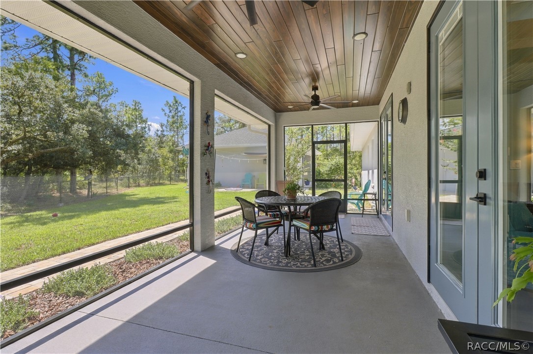 SCREENED OUTDOOR LIVING  Another view captures the impressive length of the screened lanai, wood-plank ceiling, recessed lighting & ceiling fan, all overlooking the fenced backyard. Multiple access doors make indoor/outdoor living effortless.