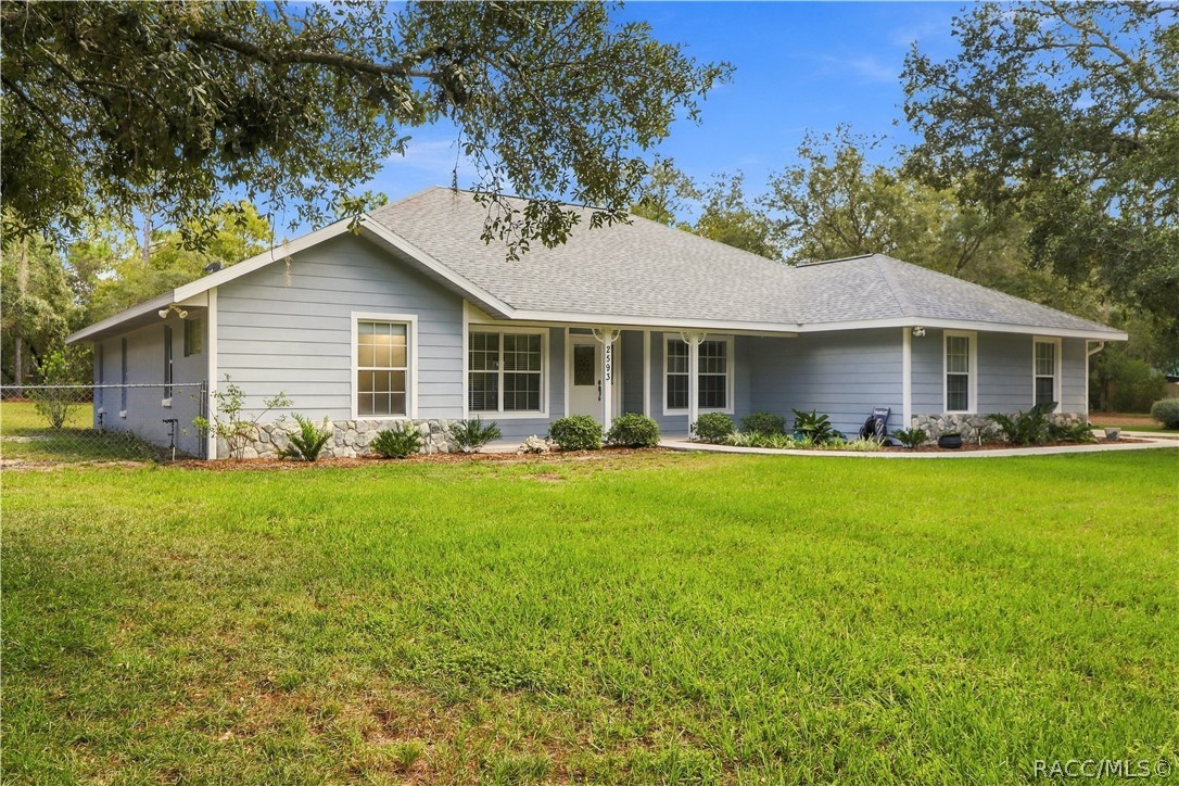 Front Exterior  BRAND NEW ROOF 2026  Attractive front view featuring a covered front porch, mature landscaping, stone accents sitting on a fully fenced 1.25 acres.