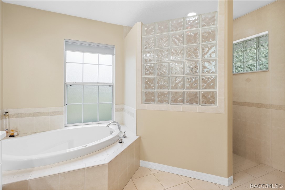 Primary Bathroom  Alternate view showcasing the soaking tub, decorative glass-block accents and separate tiled walk-in shower.