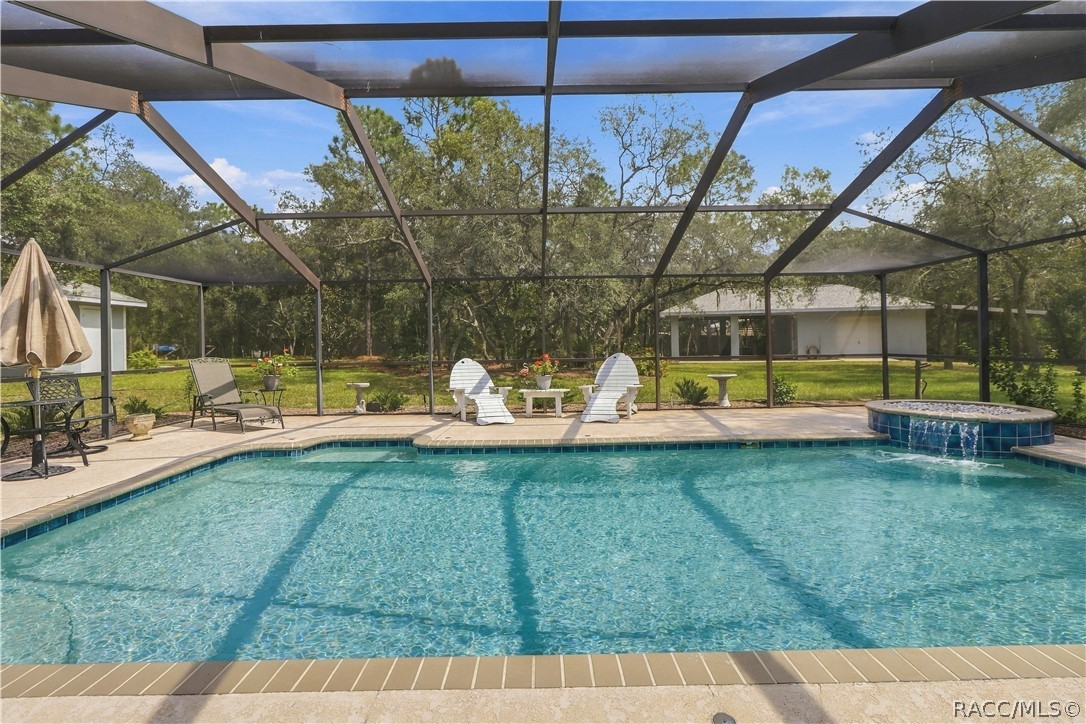 Screened Pool 14 x24 & Decorative Spillover Waterfall  Expansive screened pool area featuring a large salt water swimming pool, waterfall with spillover feature and spacious pool deck.
