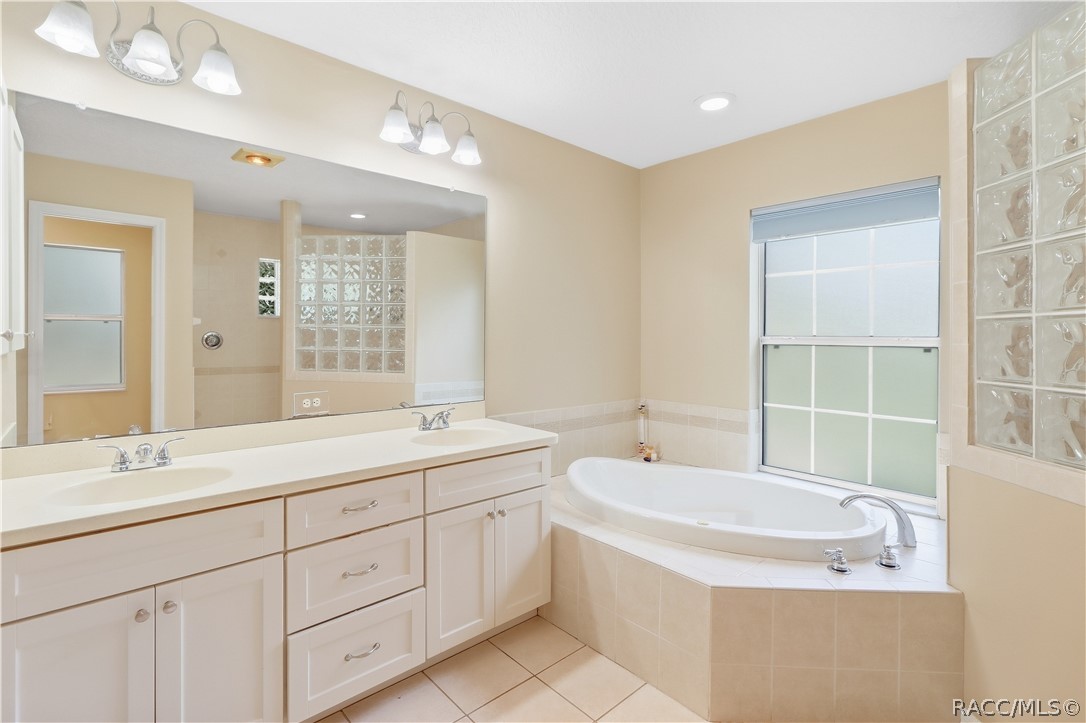 Primary Bathroom  Spacious ensuite featuring a dual-sink vanity, large mirror, soaking jetted tub and tile flooring.