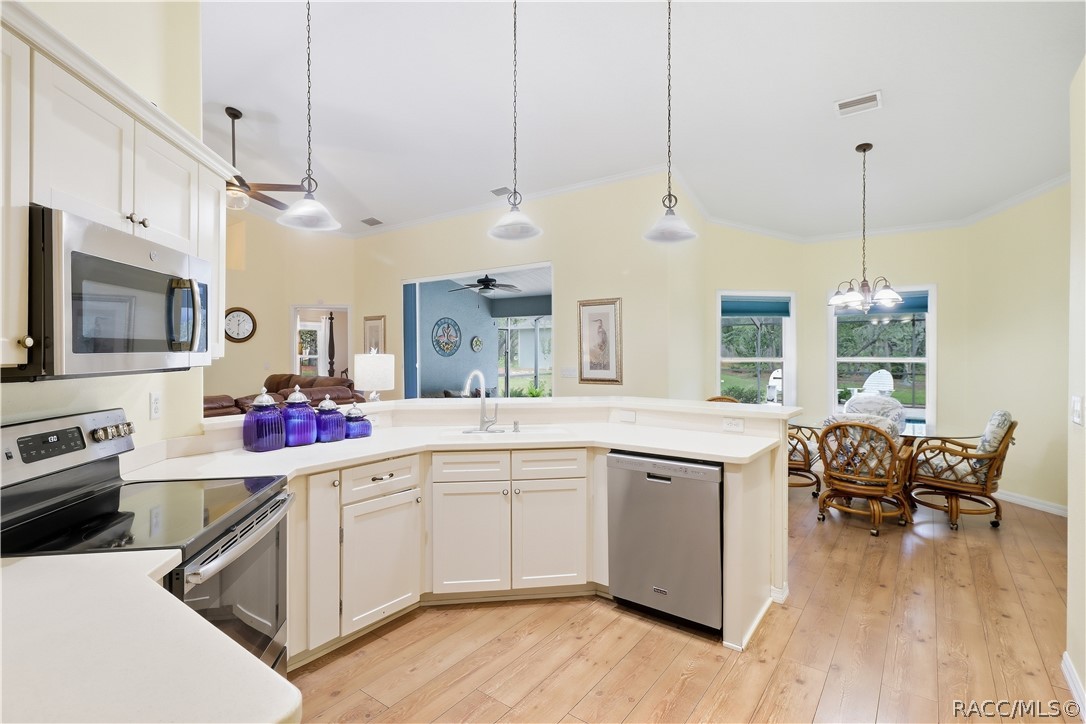 Kitchen & Kitchen Nook Area  Open kitchen featuring abundant cabinetry, corian countertops, breakfast bar, NEWER stainless-steel appliances & adjoining dining area.