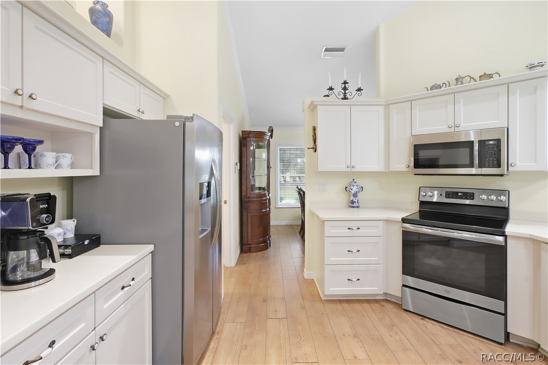 Kitchen  Bright kitchen with abundant white cabinetry, stainless-steel appliances, extensive counter space & laminate flooring.