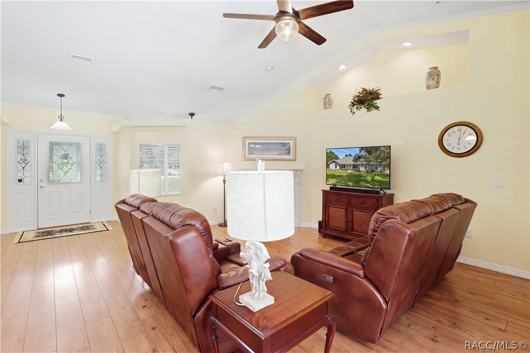 Living Room  Spacious living area with vaulted ceiling, crown molding, wood-look flooring, ceiling fan & open layout.