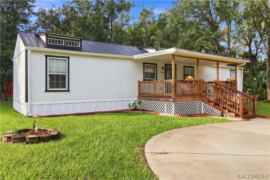 Front Exterior  Attractive white exterior w/contrasting dark trim, METAL ROOF & spacious covered wooden porch, surrounded by a lush green lawn.