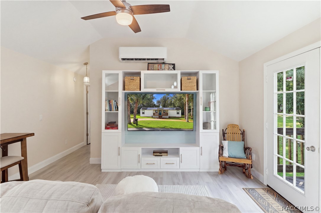 Living Room  Bright & inviting living room featuring VAULTED CEILINGS, luxury vinyl plank flooring, ceiling fan, w/entertainment cabinetry & a MINI-SPLIT HEATING & COOLING SYSTEM. French doors provide views of the backyard & access to the rear deck.