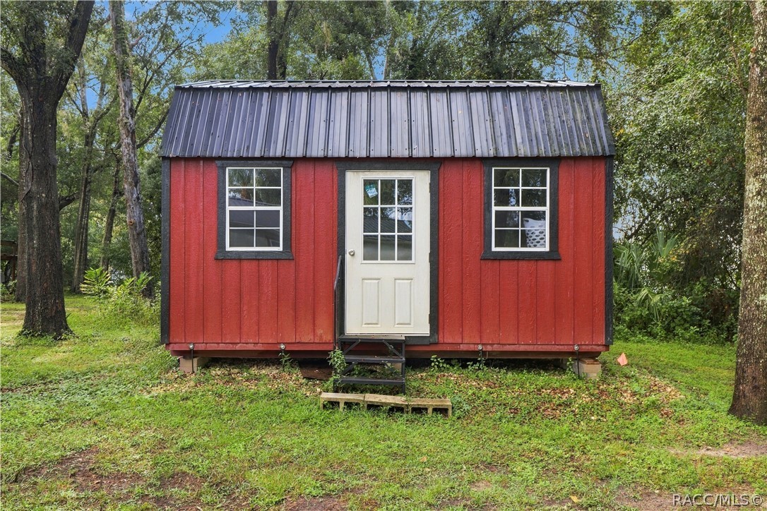Detached Storage Building  Charming RED DETACHED STORAGE BUILDING featuring a METAL ROOF, double windows & convenient entry door. A wonderful addition for storing lawn equipment, tools or outdoor essentials!