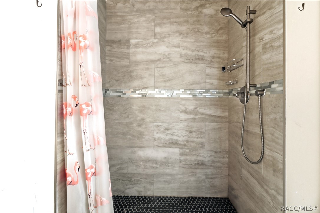 Tiled Walk-In Shower  Beautifully finished WALK-IN SHOWER featuring floor-to-ceiling tile, decorative mosaic accent band, pebble-style shower flooring & handheld showerhead.