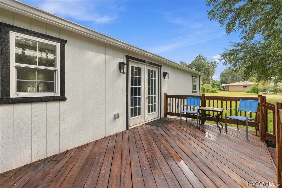 Outdoor Living  Another view of the rear deck showcasing its open layout, wooden railings & easy access to the backyard. A great setting for enjoying Florida's beautiful weather!