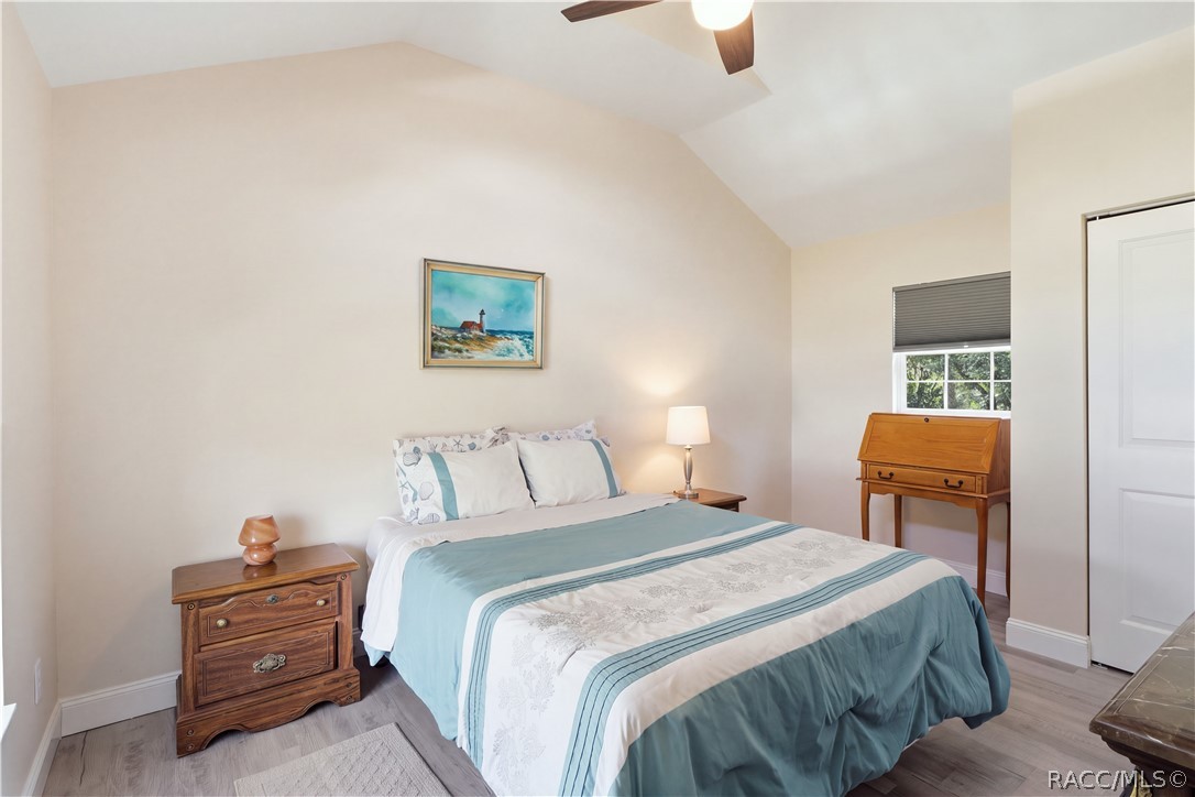 Primary Bedroom  Cozy & inviting bedroom featuring VAULTED CEILINGS, luxury vinyl plank flooring, ceiling fan & coastal-inspired furnishings.