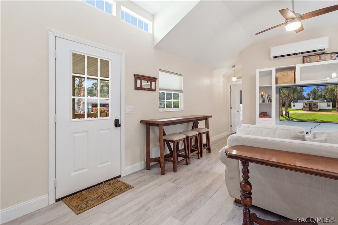 Living Area & Front Entry  Welcoming living space featuring VAULTED CEILINGS, high transom windows, ceiling fan, attractive flooring & a convenient seating area near the front entrance.