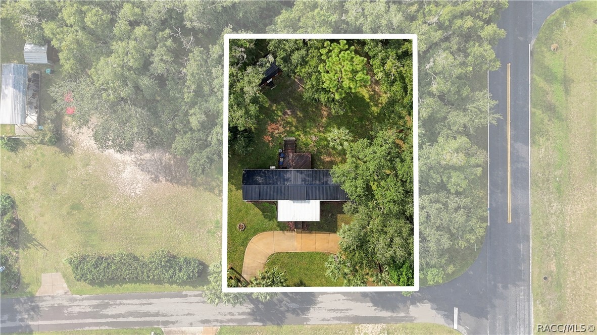 Aerial Property View  Overhead perspective showcasing the home on its .29-ACRE CORNER LOT, surrounded by mature trees, greenery & a circular driveway.