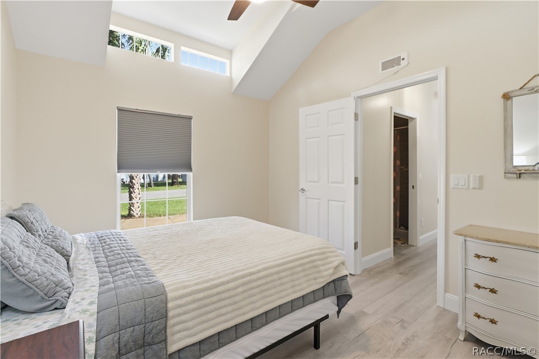 Bedroom  Comfortable bedroom featuring VAULTED CEILINGS, luxury vinyl plank flooring, ceiling fan, spacious double closets & attractive furnishings.