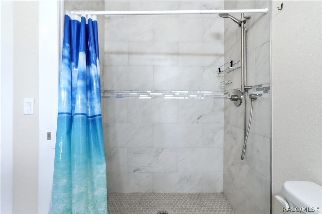 Primary Bathroom Shower  Beautifully tiled WALK-IN SHOWER featuring marble-look wall tile, decorative mosaic accent & handheld showerhead.