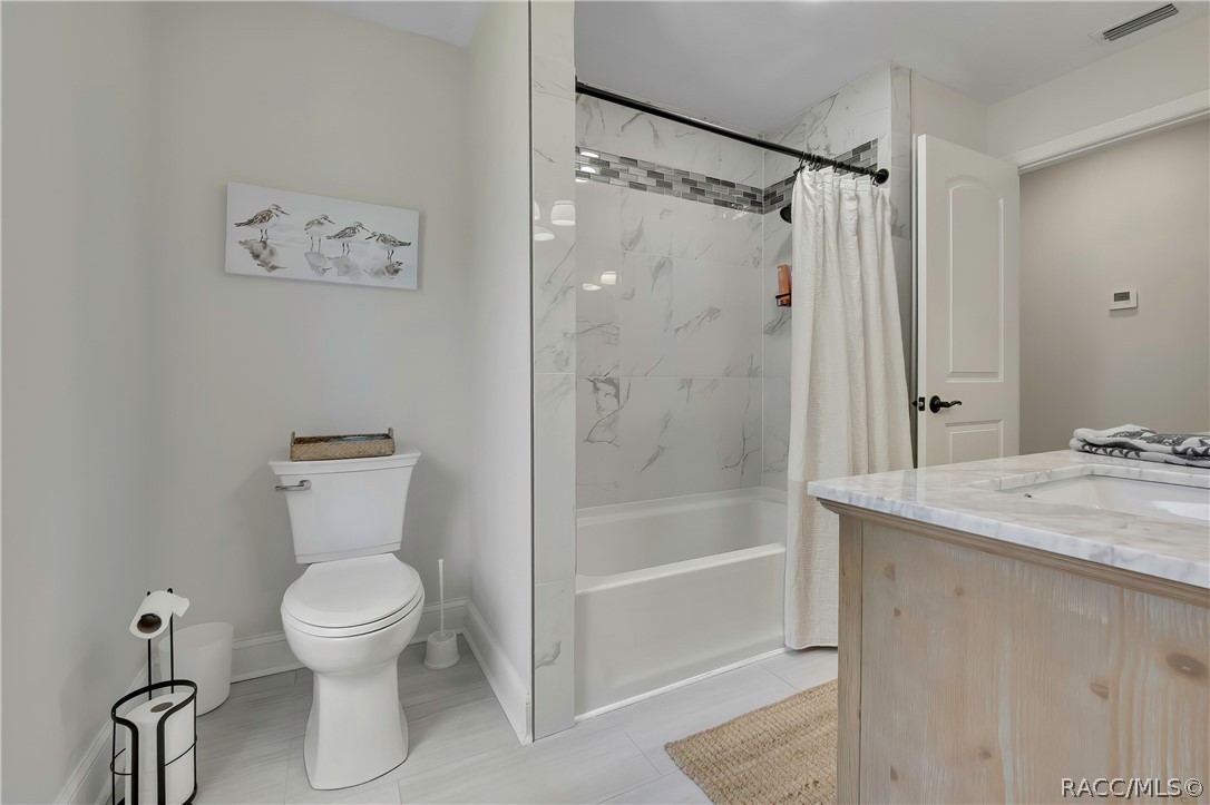 Bathroom with toilet and tub/shower with glass doors.