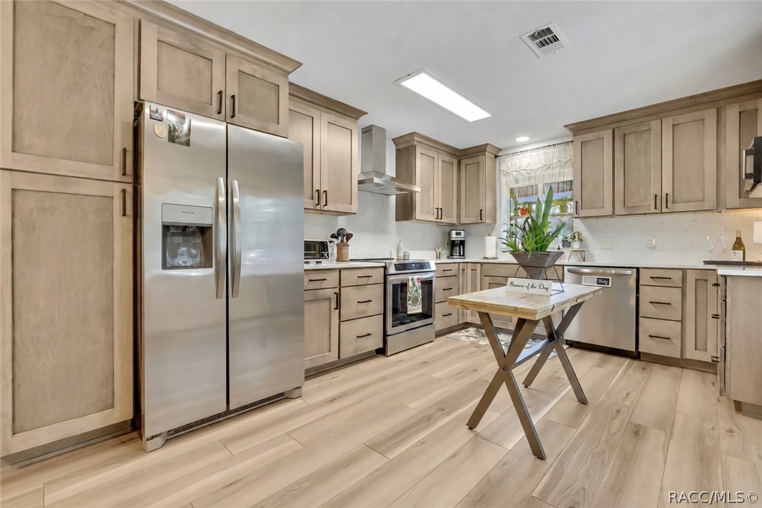 Kitchen with light wood cabinets and stainless refrigerator