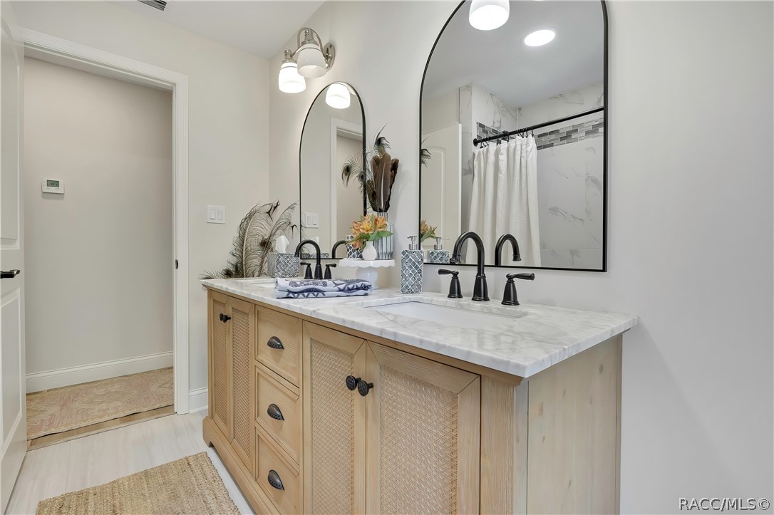 Double vanity with arched mirrors and light wood cabinets.