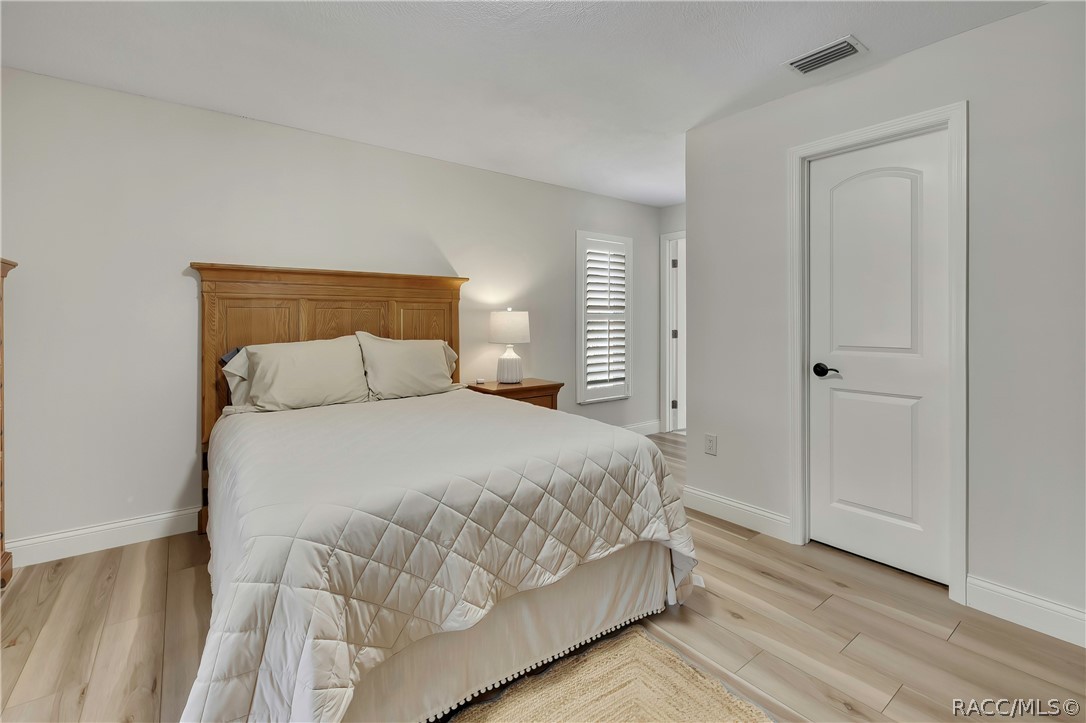 Bedroom with wood headboard and wood-look floors.