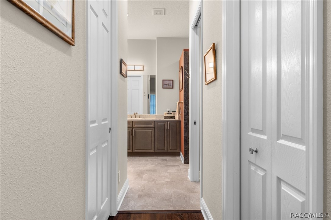 The primary suite hallway leading to the ensuite bath is flanked by walk-in closets on either side.