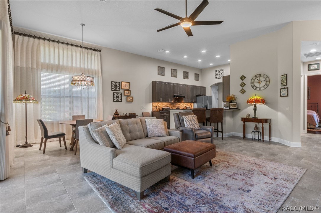 View of the greatroom and kitchen upon exiting the primary suite. On the right of this picture is a glimpse down the guest hall to the guest bedroom.
