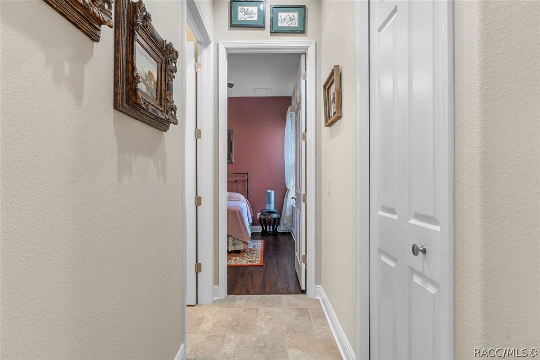 The guest wing hallway, situated just off of the great room, features a hall closet and access to a full guest bath on the left.