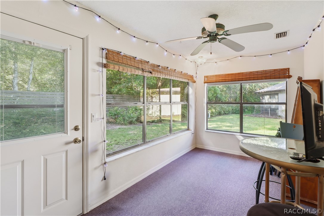 Enclosed rear porch with windows overlooking the backyard and sliding glass doors connecting to the interior.