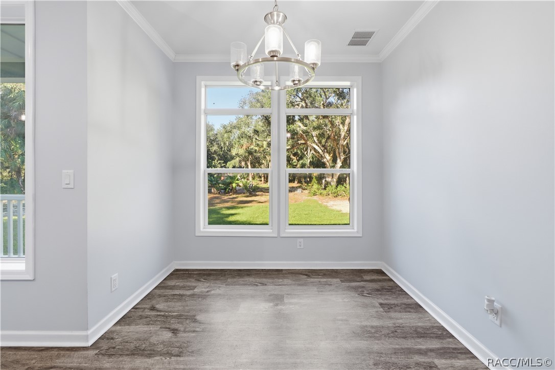 GATHER AROUND THE TABLE! The DINING AREA features a contemporary chandelier, attractive flooring & large windows framing views of the wooded property.