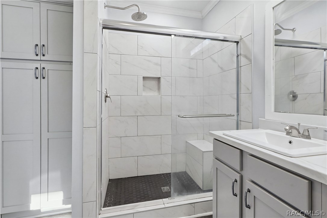 A SHOWER DESIGNED FOR COMFORT! The WALK-IN SHOWER features marble-look tile, a rainfall-style showerhead, glass sliding doors, built-in seating & a convenient recessed niche.