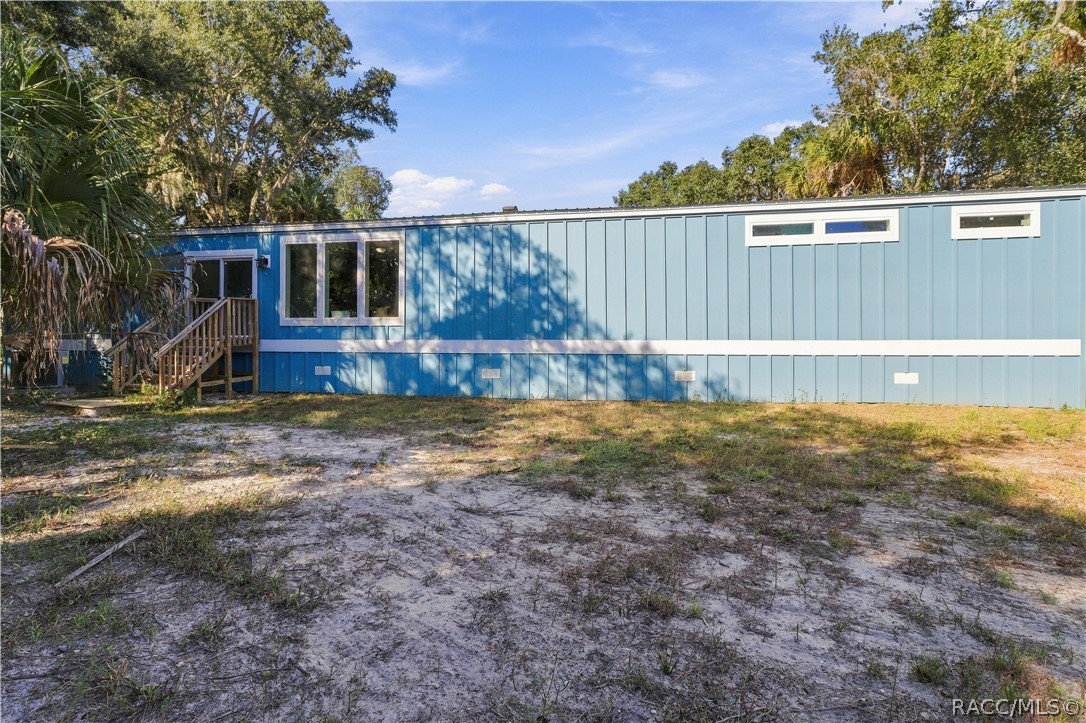 COUNTRY CHARM & ROOM TO ROAM! Another exterior view showcases the home's spacious setting, attractive siding, rear steps & surrounding greenery.