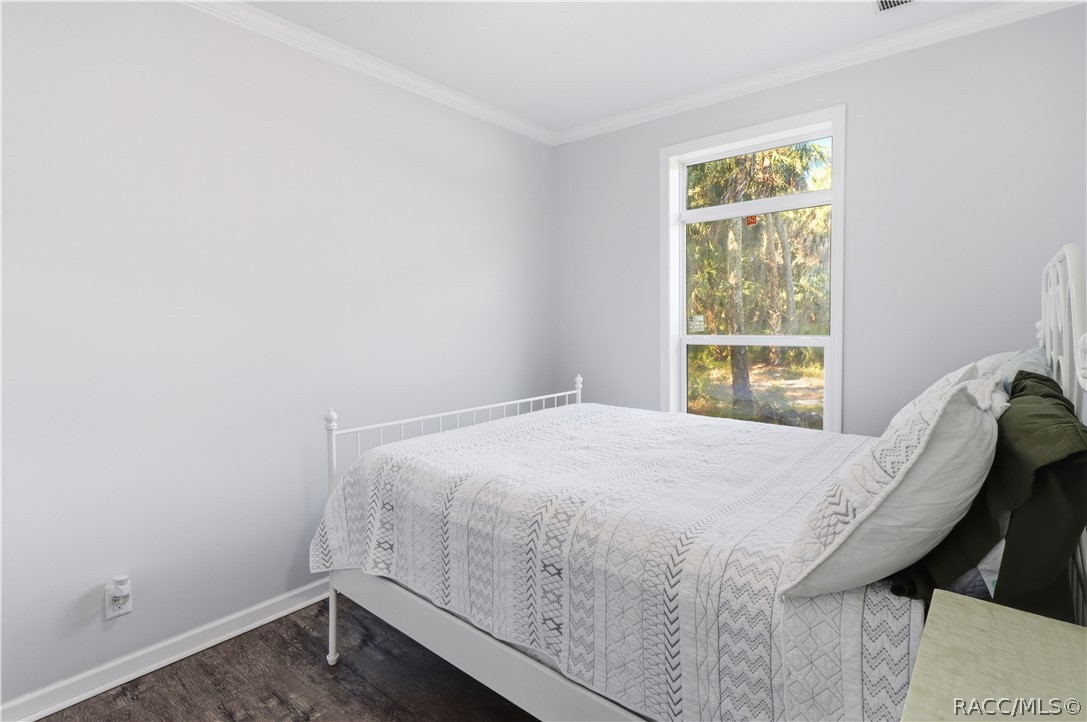 WAKE UP TO NATURE! Another view of the bedroom showcases natural light, attractive flooring & peaceful views of the surrounding trees.