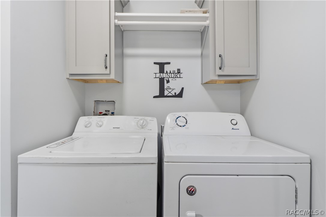 LAUNDRY MADE CONVENIENT! The INDOOR LAUNDRY AREA features a washer, dryer, overhead GRAY CABINETRY & shelving for additional storage.