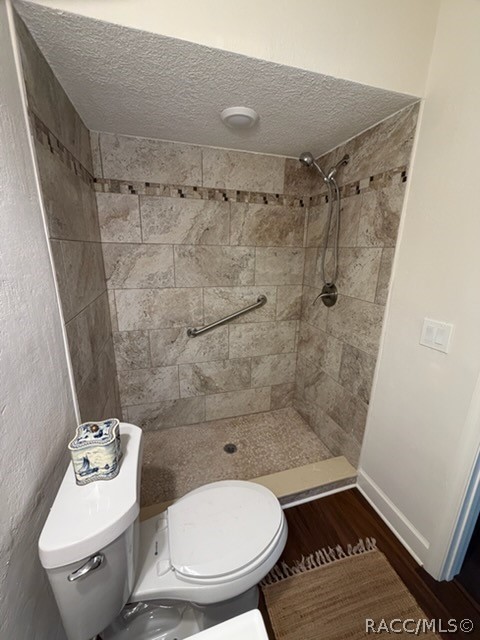 Bathroom: white vanity with a modern chrome faucet, a navy-and-white towel hanging over the vanity, a white toilet with a patterned container on the tank, a walk-in shower with stone-look tile walls, a mosaic accent strip, a grab bar and a pebble floor with a drain, recessed ceiling lights, and a 2-light fixture at the top left. This is the single-sink hall bath, not the primary bath.