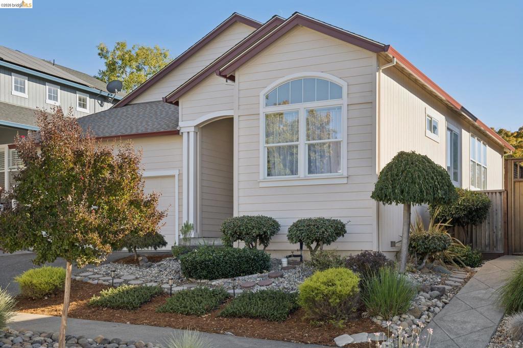 Single-story residence featuring horizontal lap siding, a covered entryway, an arched window, a multi-gabled roofline, and landscaped rock-mulch front yard