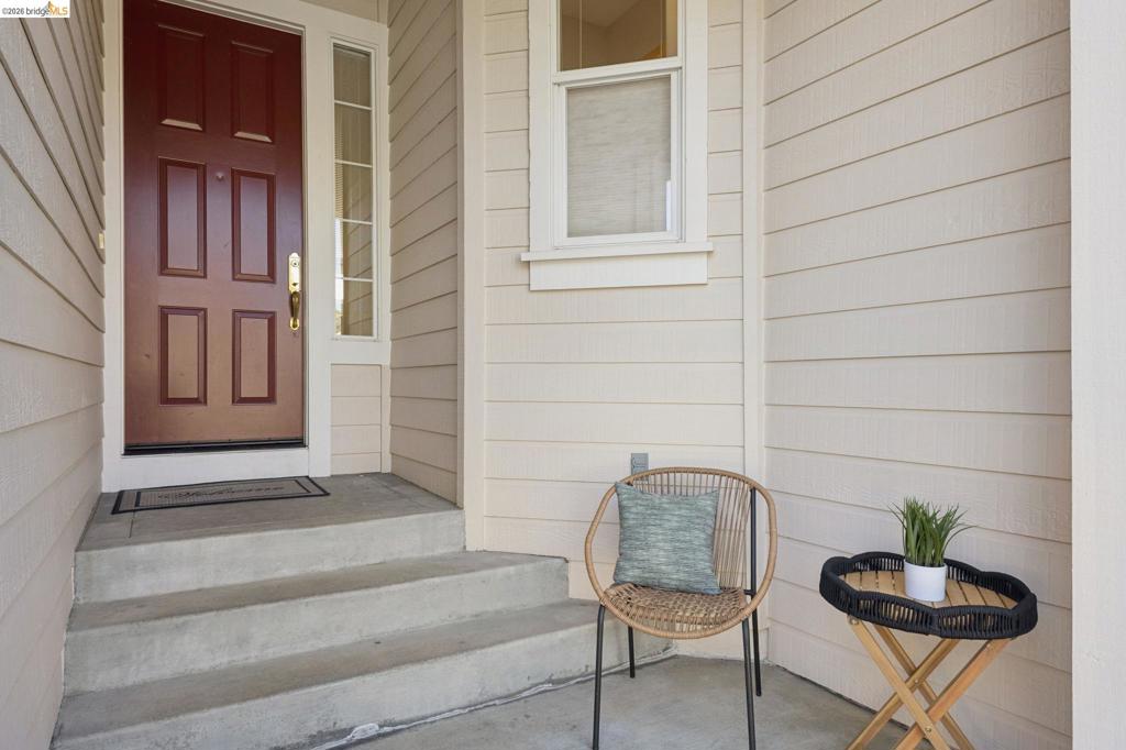 Covered entryway featuring horizontal lap siding, a paneled door with glass side light, and concrete stairs