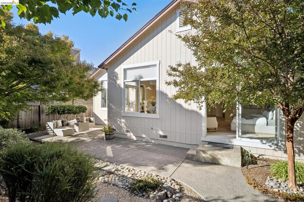 Exterior featuring vertical siding, concrete hardscaping, stone-accented landscaping, and large windows