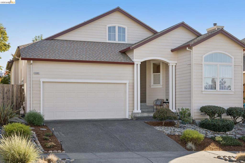 Single-story residence featuring light-toned horizontal siding, a multi-gabled roofline, an attached two-car garage, and an arched entryway with decorative columns
