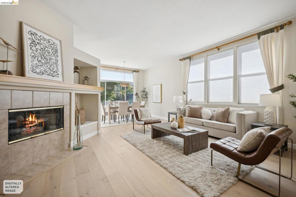 Fireplace with neutral ceramic tile surround, integrated shelving, light wood-finish flooring, and expansive multi-pane windows