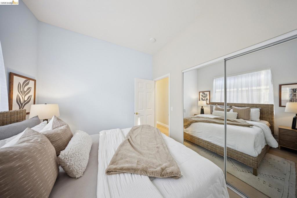 Bedroom featuring high ceilings, neutral wall tones, and floor-to-ceiling sliding mirror closet doors