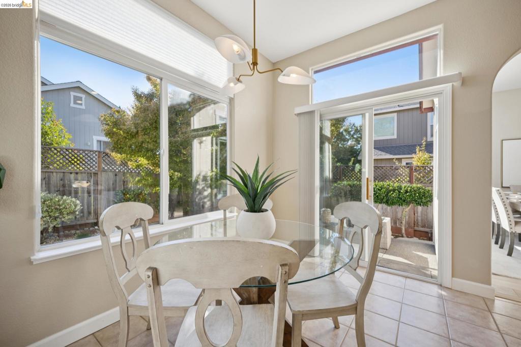 Large windows, sliding glass door, multi-arm metal chandelier, and ceramic tile flooring