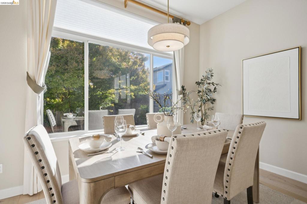 Large multi-pane window with a neutral pleated shade, three-tier drum pendant light fixture, and wood-finish flooring