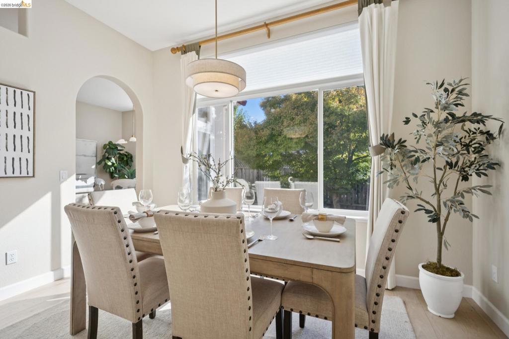 Large picture window with horizontal transom, architectural arched doorway, drum pendant light fixture, and wood-finish flooring